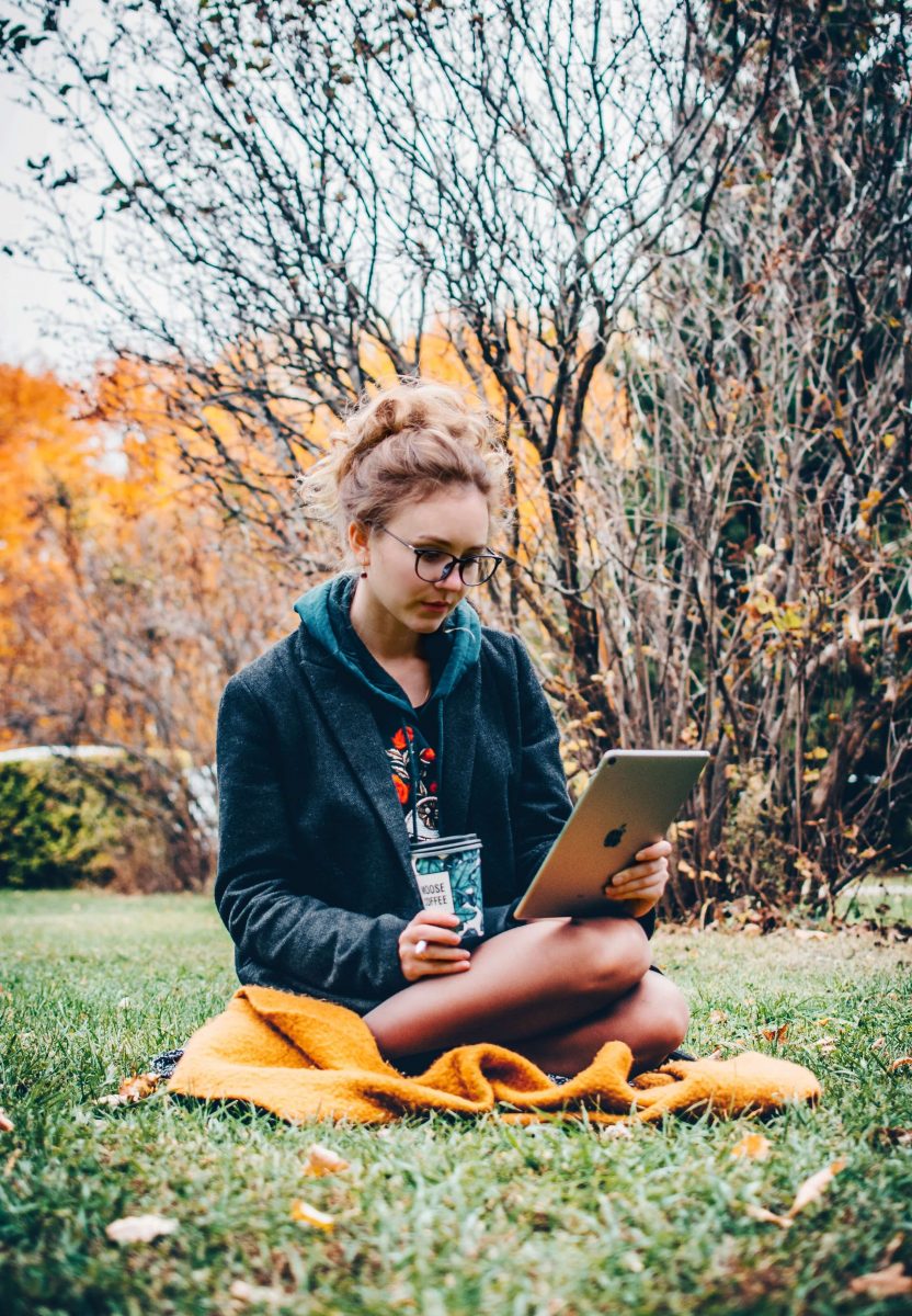 meisje op haar iPad in een park met een gele deken